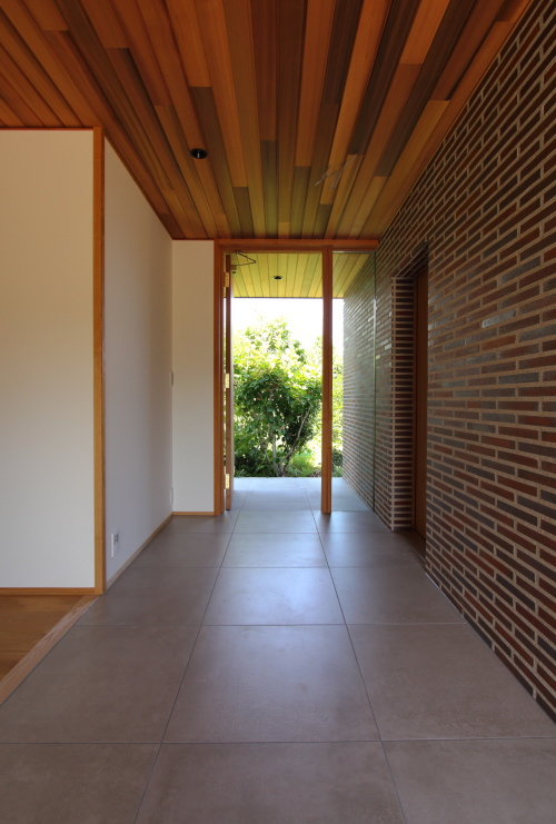 早島にて完成した注文住宅、木製建具とタイル、植栽が爽やかなフラット玄関